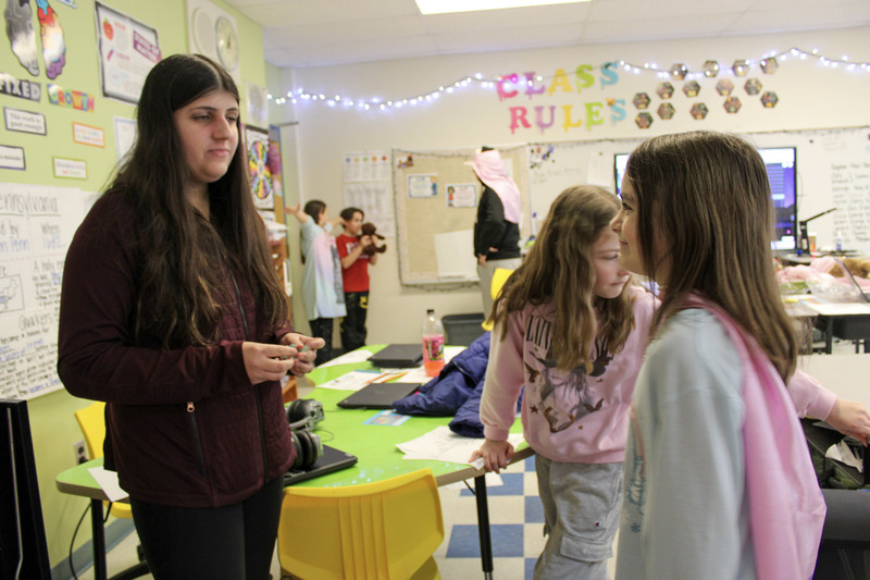 Female high school student working with two young female students