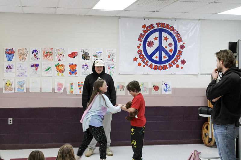 Male high school student working with a younger male and female student with an adult standing by