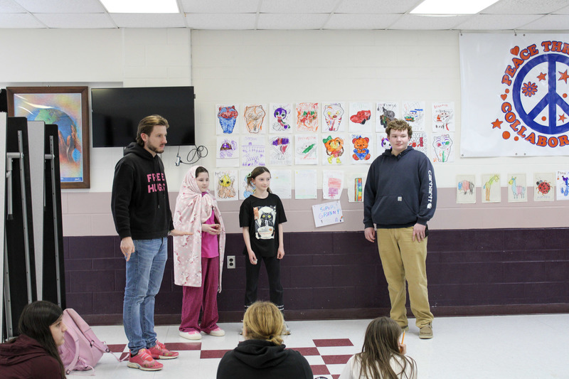 Male high school student standing next to a  younger male and female student with a male adult 