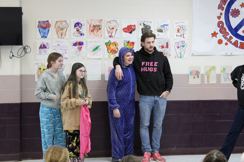 Two young female students standing next to a young male student and an adult male