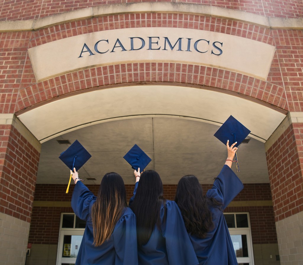 Three graduates in a line, wearing their graduation regalia.