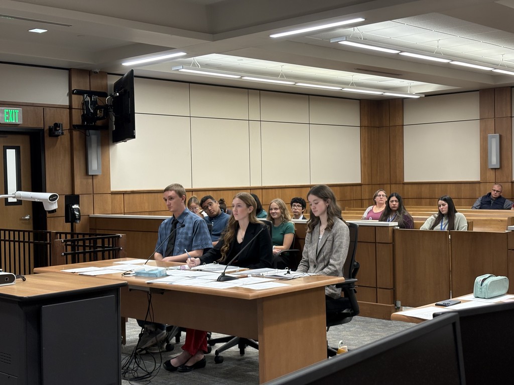 Defense team sitting at table listening to direct examination.