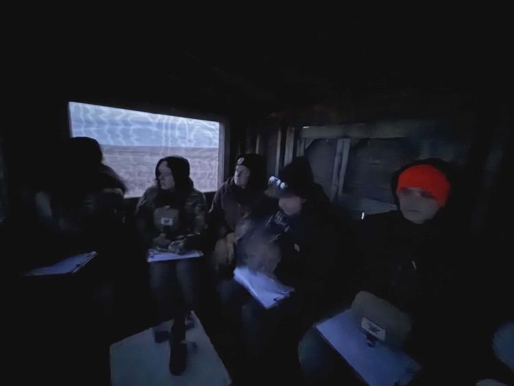 A dark picture of kids sitting in a blind, waiting for the grouse to come dance on the dancing grounds
