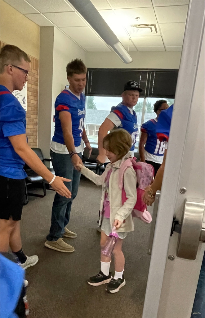 student football player giving high fives to younger students