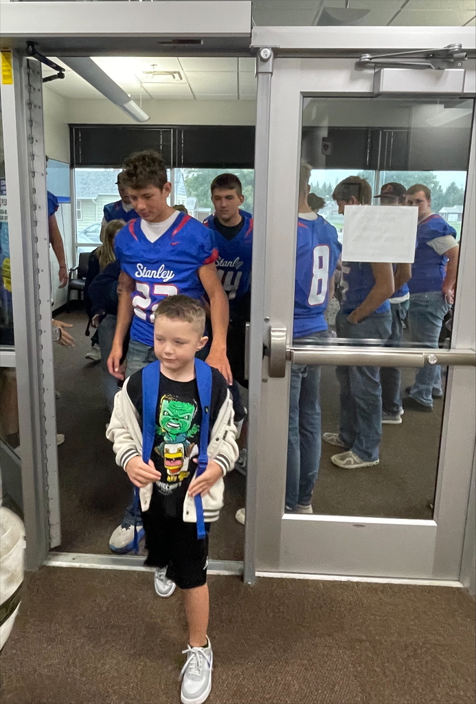 student football players giving high fives to younger students