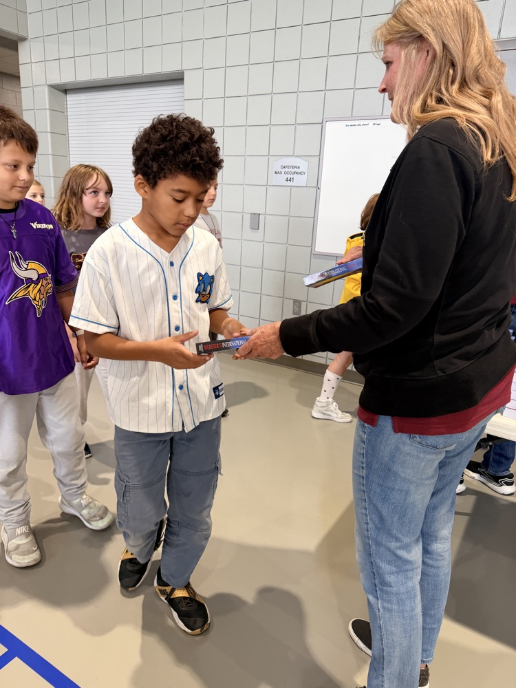 3rd grader being handed Atlas 