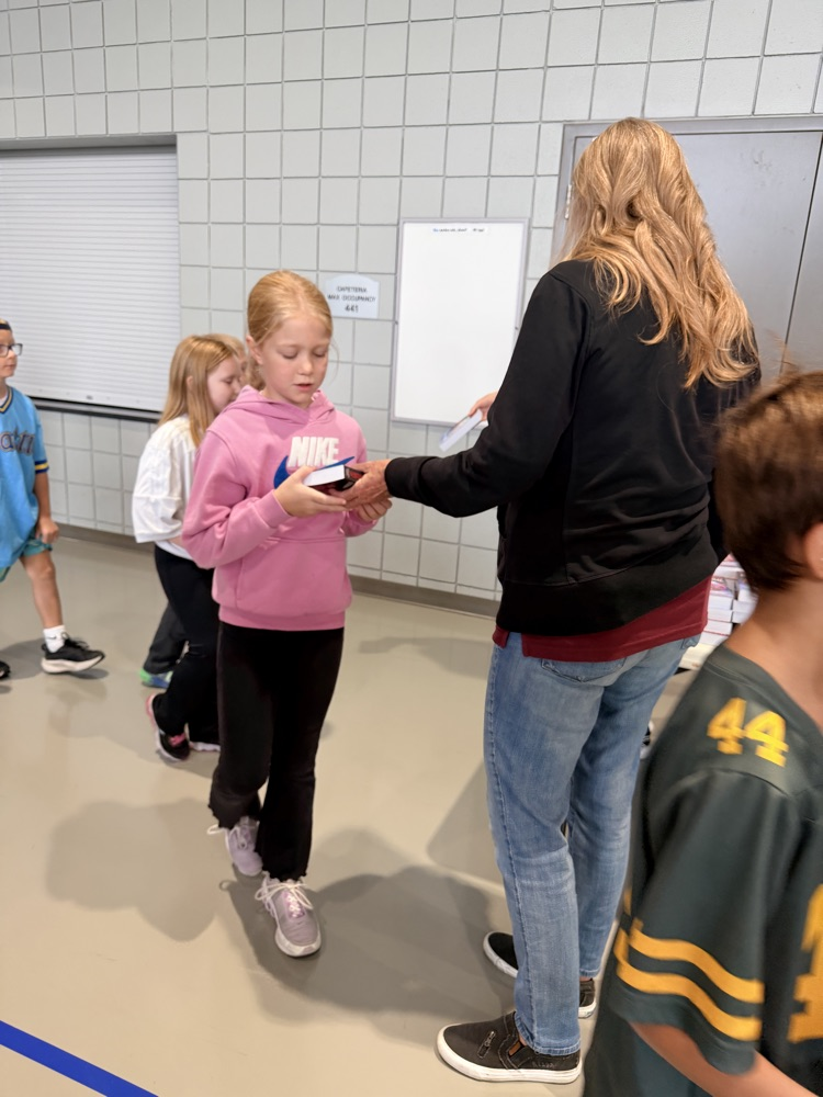 3rd grader being handed Atlas 