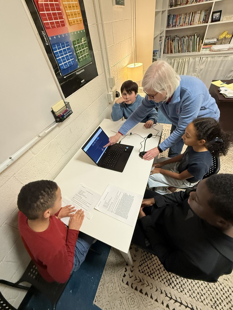 Mrs. Anderson works with a group of students as they record their podcasts.
