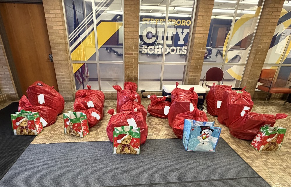 A collection of wrapped holiday gifts arranged on a table in the Streetsboro City Schools office lobby