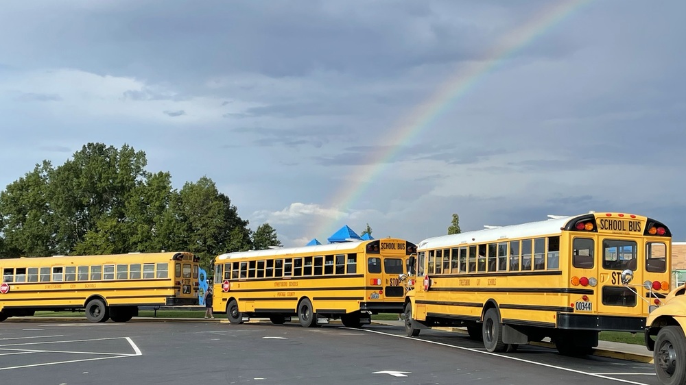 school buses with rainbow in the background