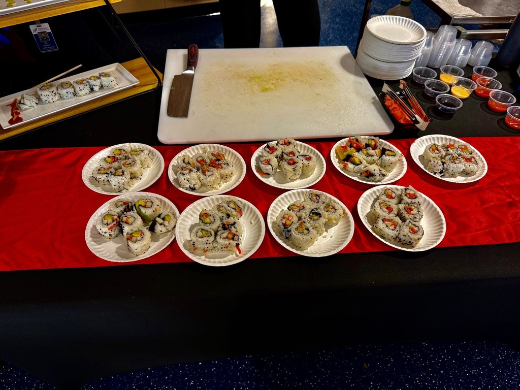 Photo of plates of sushi on a table sitting on a red table runner. 