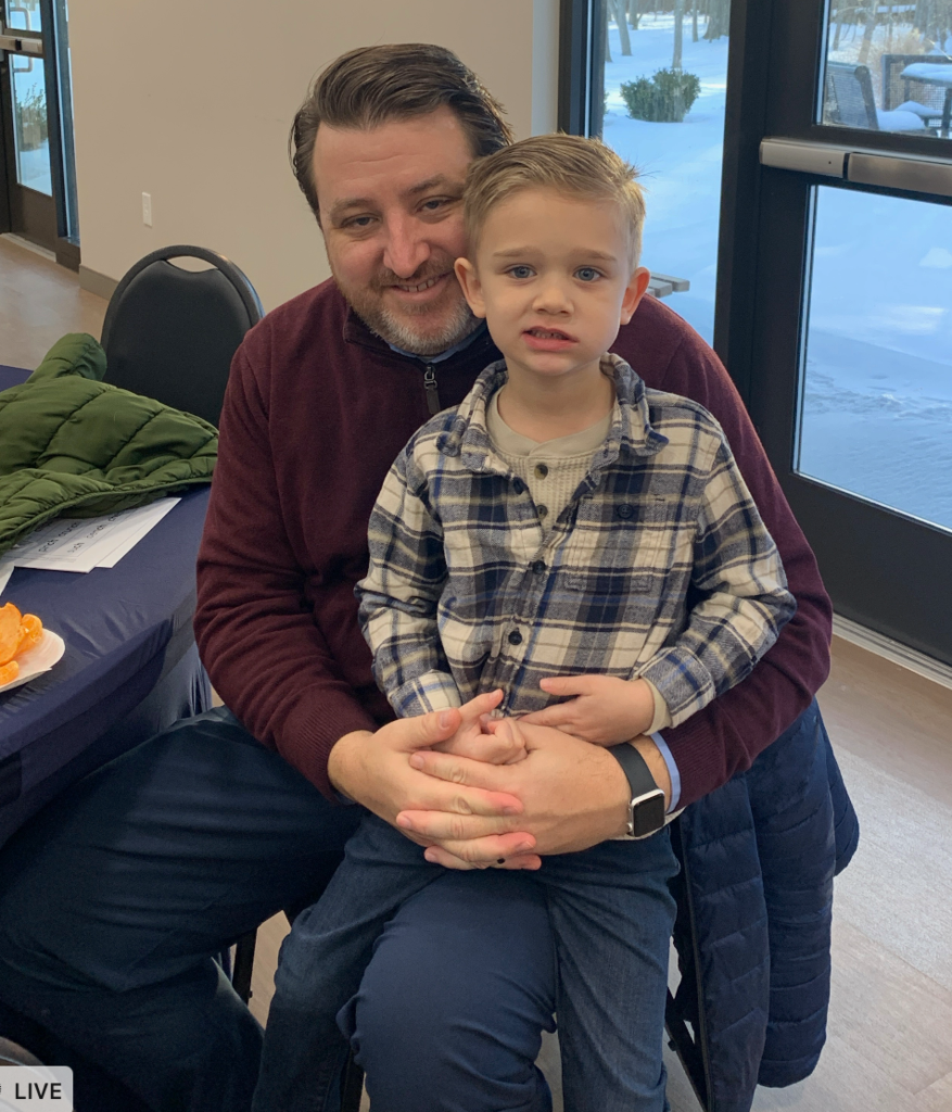 Families sitting around tables with breakfast items and coloring pages on the tables in front of them