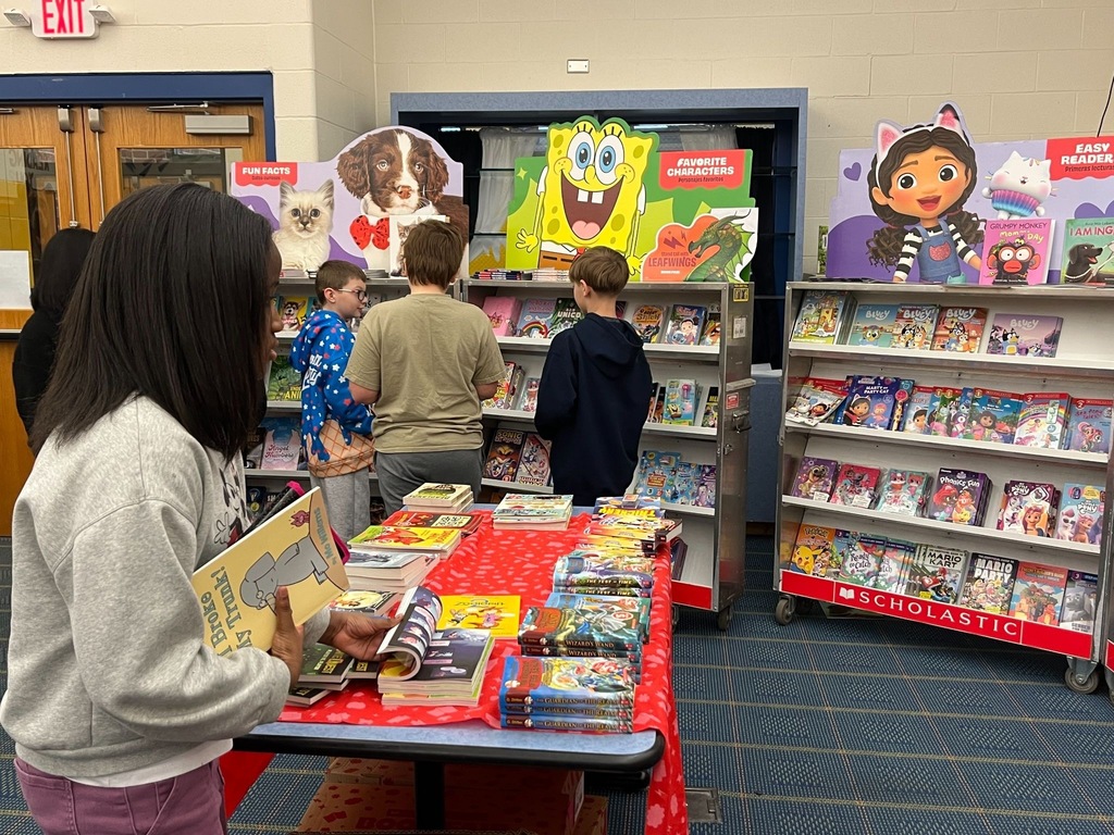 Students are looking at all the books for sale at the scholastic book fair. 