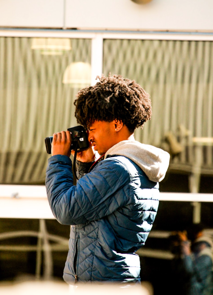 Student holding a camera and capturing a photo.