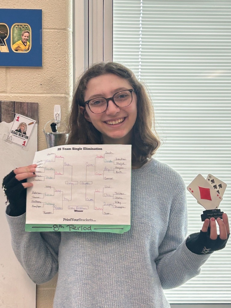 A smiling middle school student holds up a single-elimination tournament bracket labeled "8th Period" and a small handmade trophy decorated with playing cards. The bracket is titled "25 Team Single Elimination" and lists student names throughout the rounds.