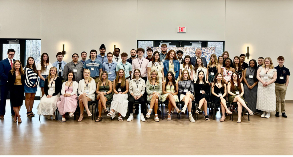 a group photo with three rows of students. The first row is students sitting on chairs.
