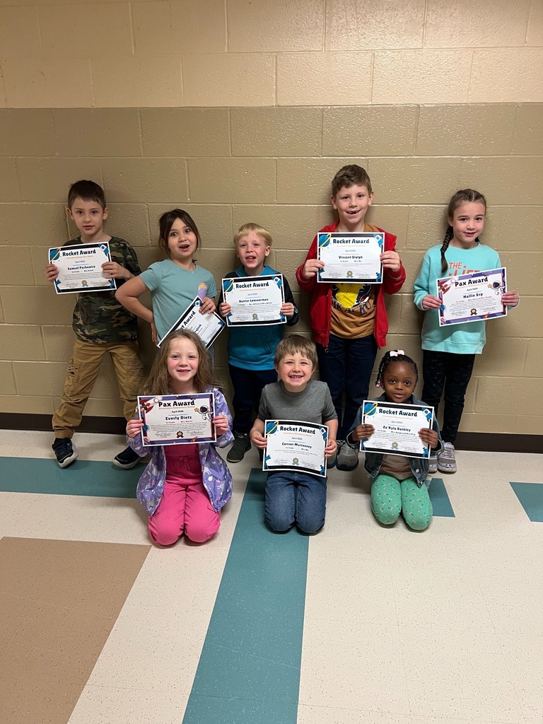 Students in two rows in a hallway holding certificates