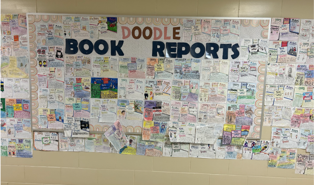 A hallway wall at Streetsboro Middle School is filled with colorful student doodle book reports featuring characters, summaries, and illustrations.