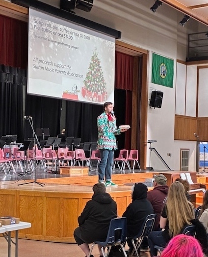Auctioneer on stage auctioning off a pie.