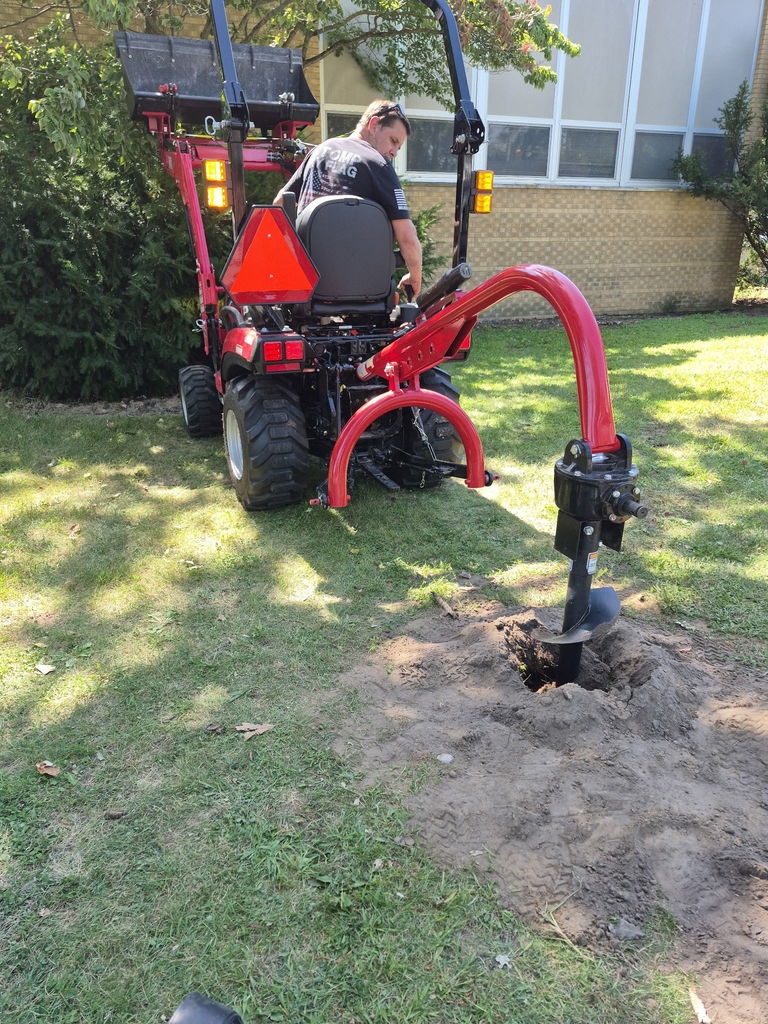 Mr. Wherry digging a hole with his tractor and auger.