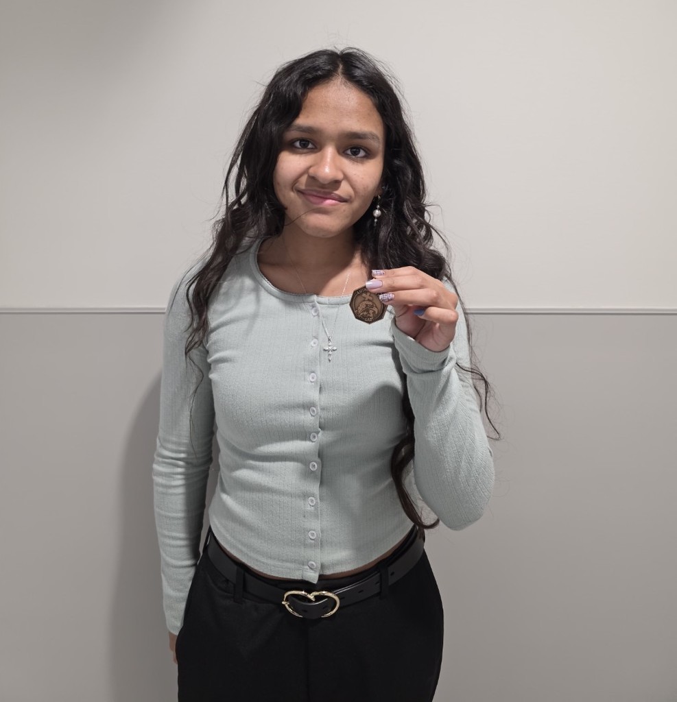 A girl holding up a 6th place medal.