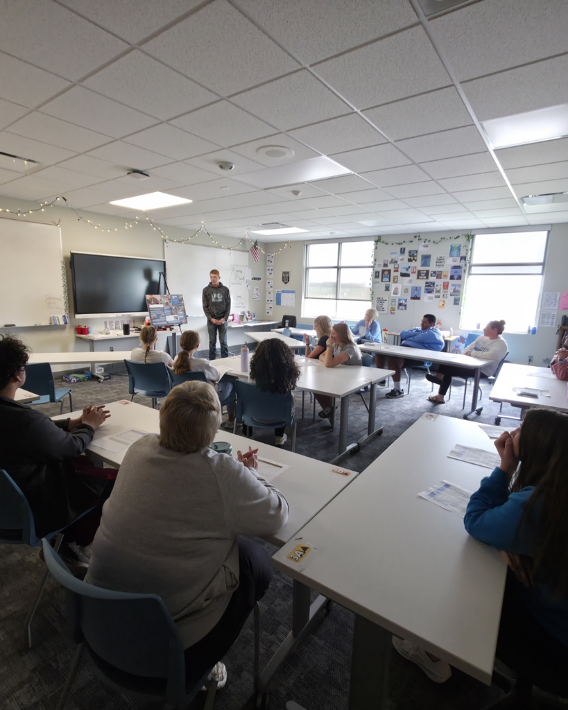 A senior in high school shares a presentation for a large audience.