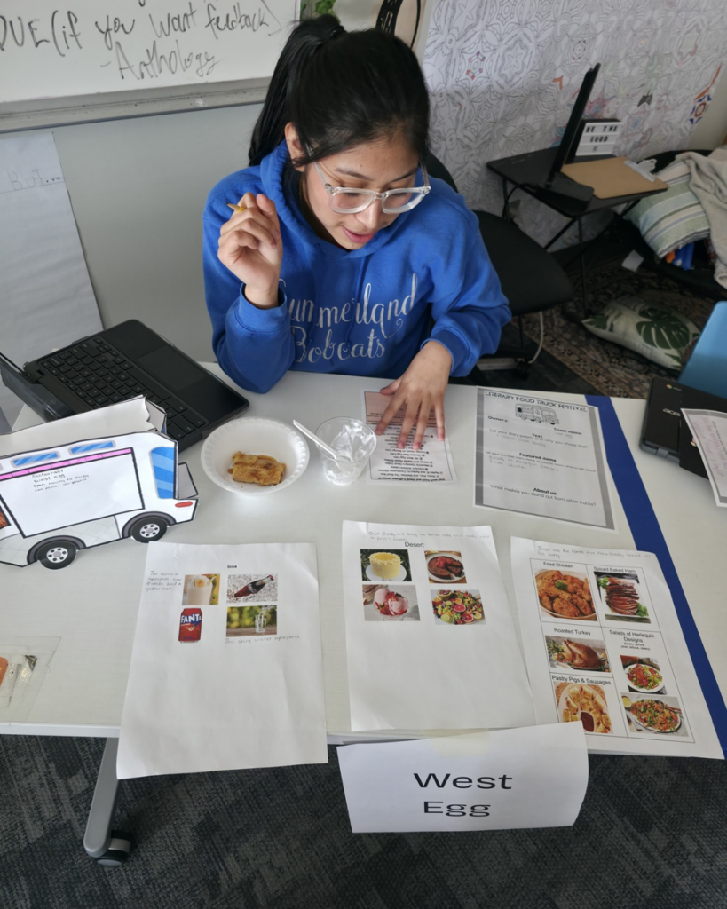 A girl wearing a blue Summerland Bobcats sweatshirt presenting her food truck called "West Egg".