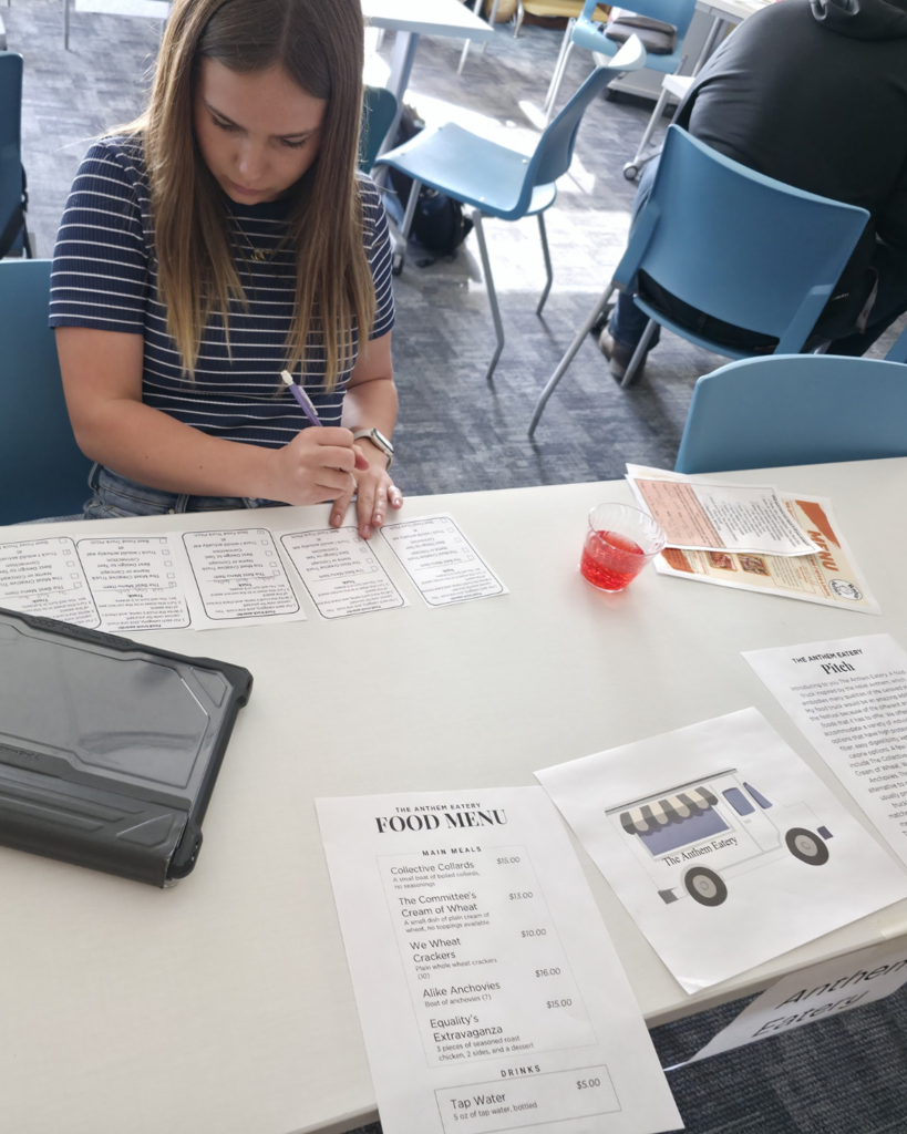 One girl wearing a shirt with blue and white vertical stripes is presenting her truck and voting on awards on small sheets of paper.