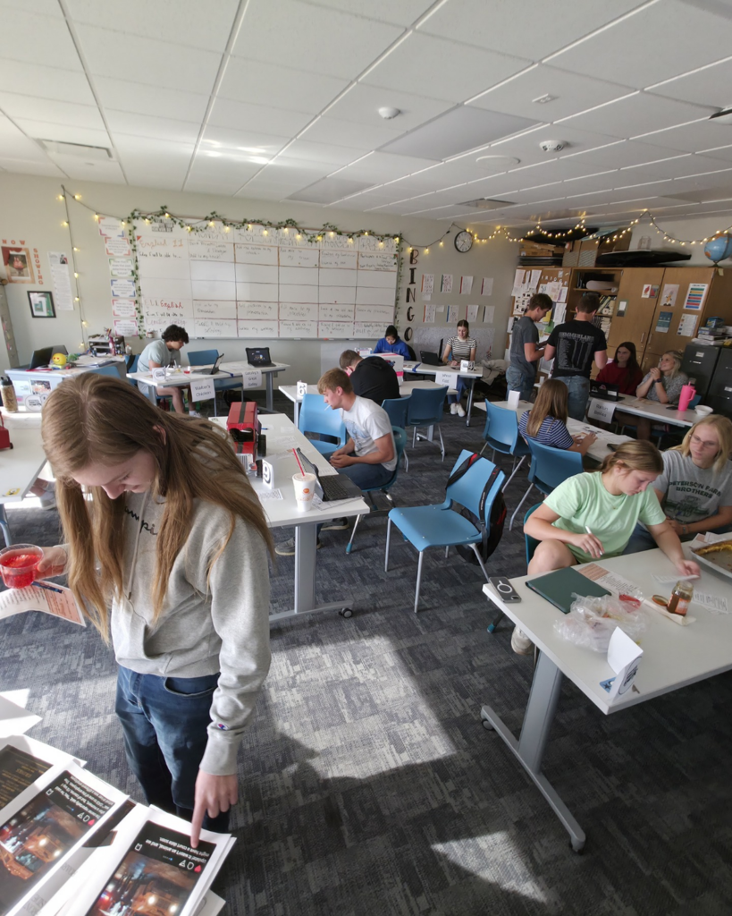 Several students presenting their ideas in a round group setting in a classroom. Other students are listening to their presentations.