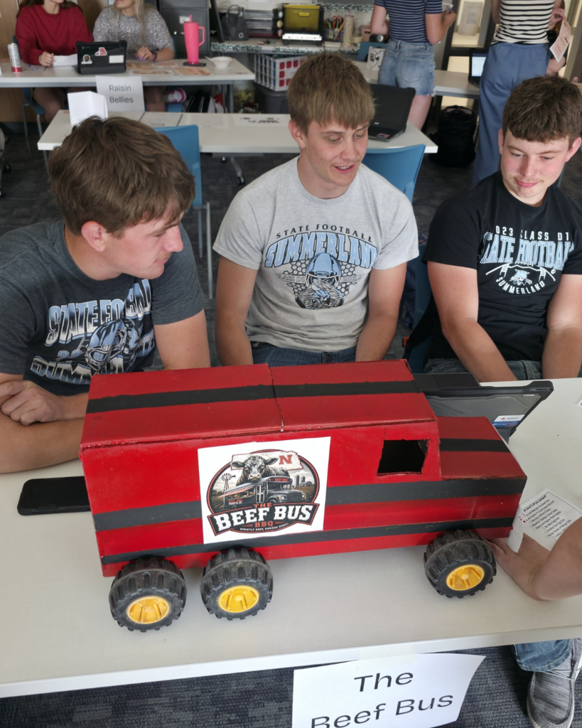 Three boys in Summerland t-shirts present their 3D food truck called "The Beef Bus"