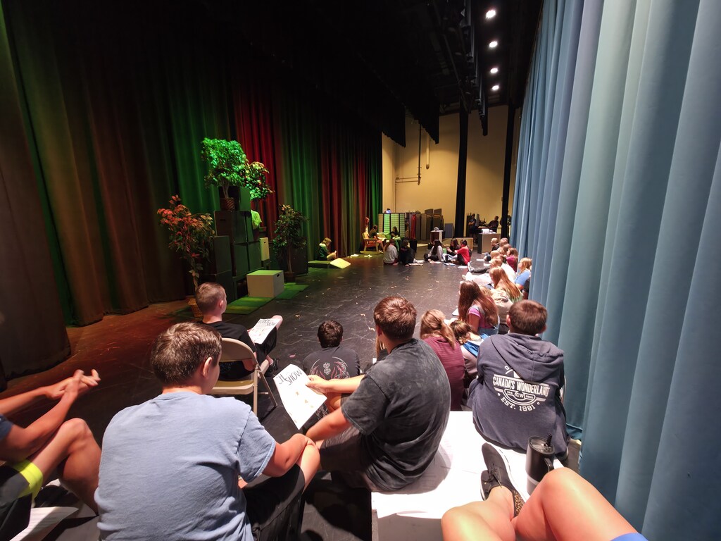A large audience watches a mini performance on a stage.