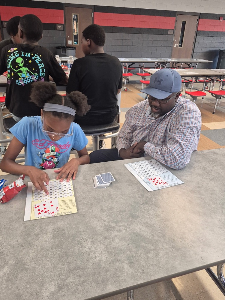 students and principal sitting at the table working on a game
