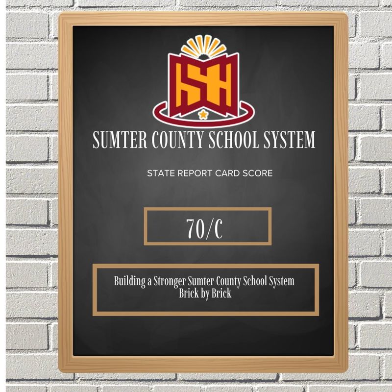 Chalkboard display with "Sumter County School System" and a logo on top. Text reads "State Report Card Score: 70/C" and "Building a Stronger System Brick by Brick."