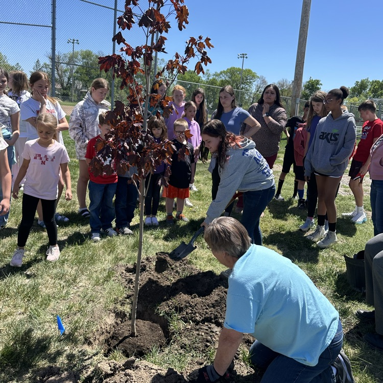 Fifth graders filling the hole with dirt.