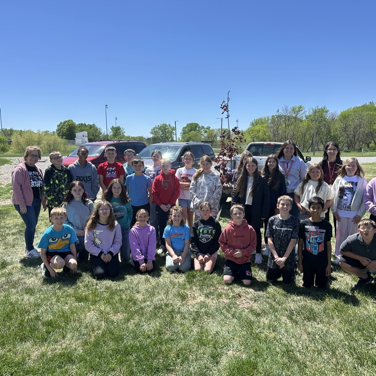 Fifth graders standing by the tree they helped to plant.