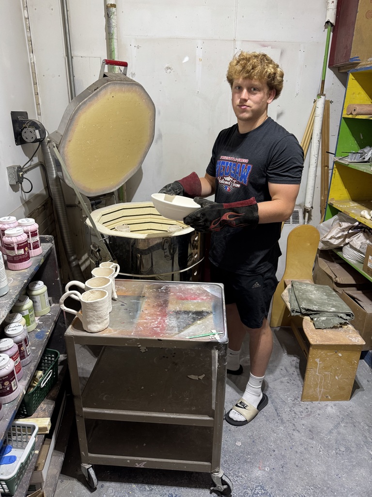 Student helping unload a still warm kiln