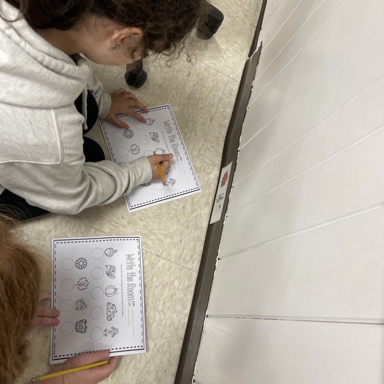 Two fifth graders decoding a hidden picture on the wall.