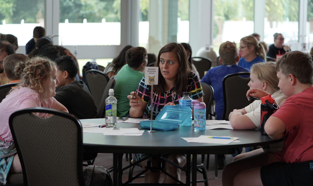Students gather around table to discuss ideas