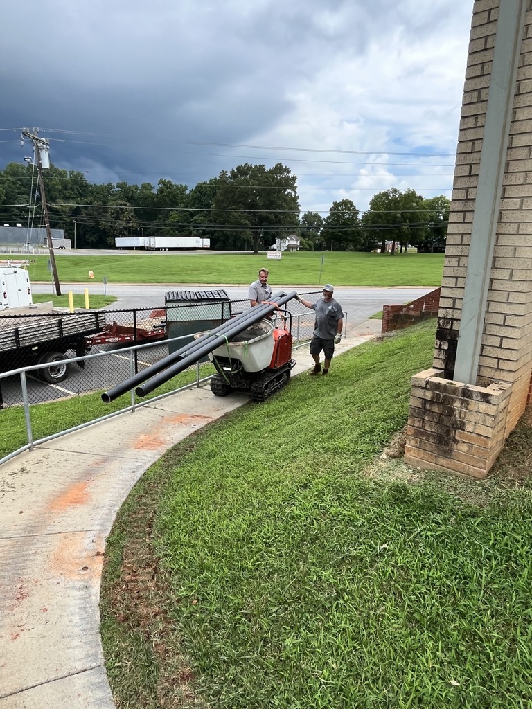 Two maintenance team members work on putting sun shades in place at Dobson