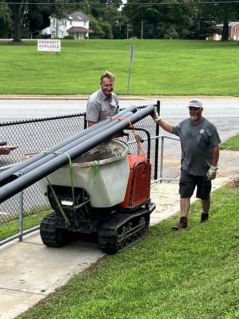 Two maintenance team members work on putting sun shades in place at Dobson