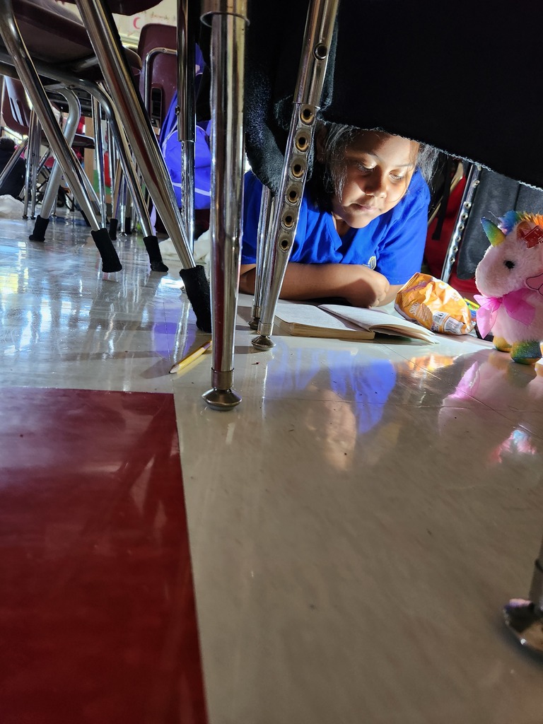 student reading under their desk by flashlight