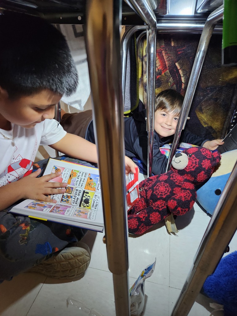 students reading under their desk by flashlight