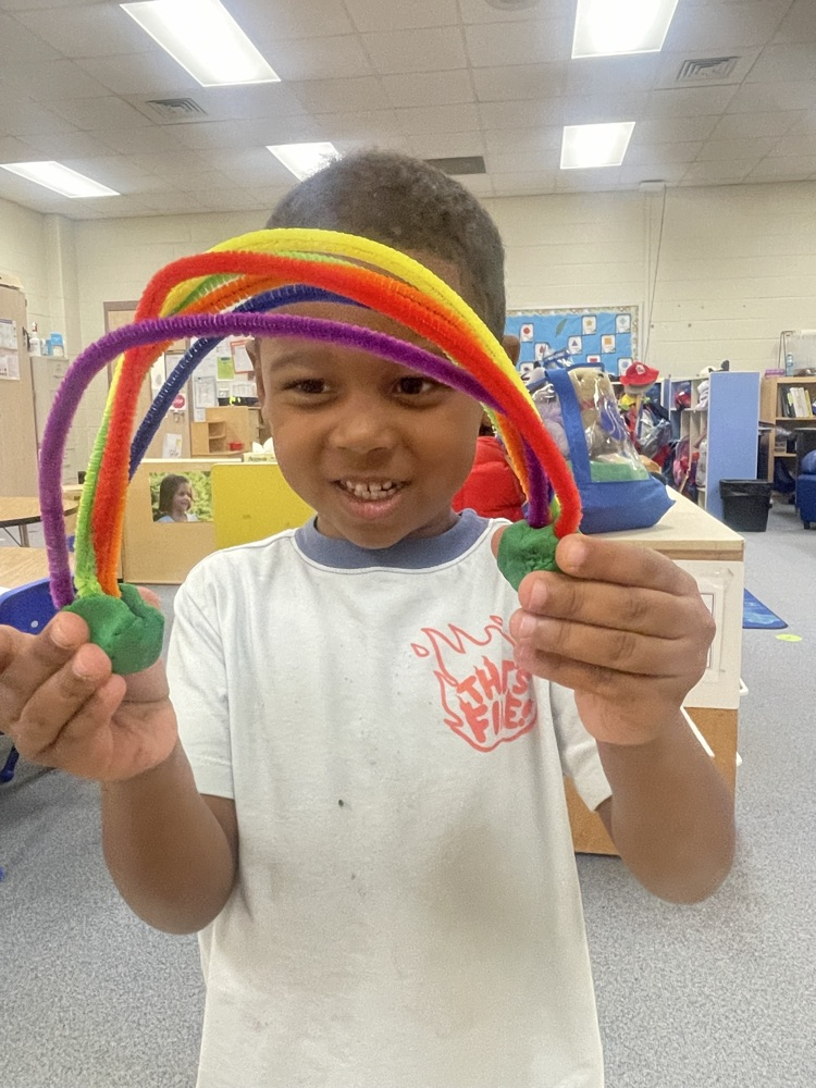 student holding a pipe cleaner rainbow
