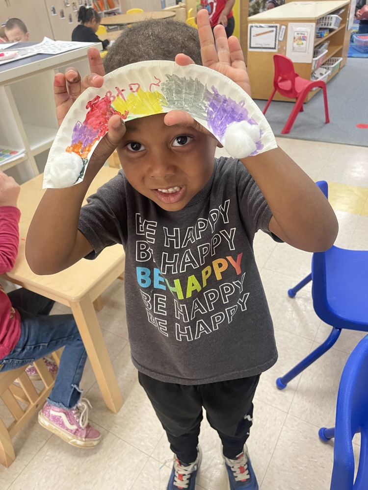student holding a painted paper plate rainbow 