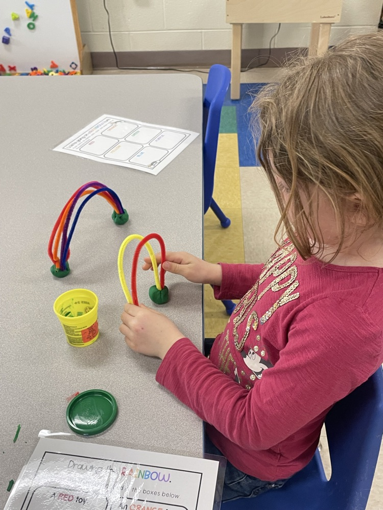 student creating a pipe cleaner rainbow with play doh