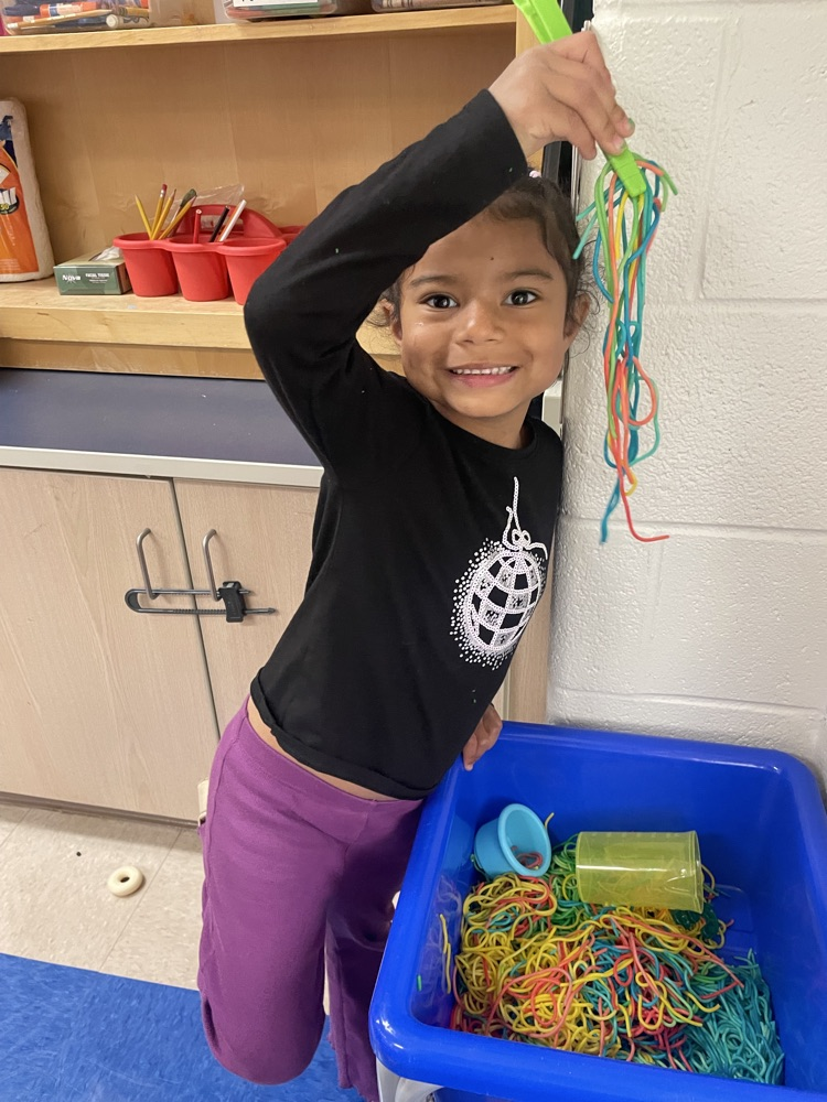 student using tweezers to hold up rainbow colored string 