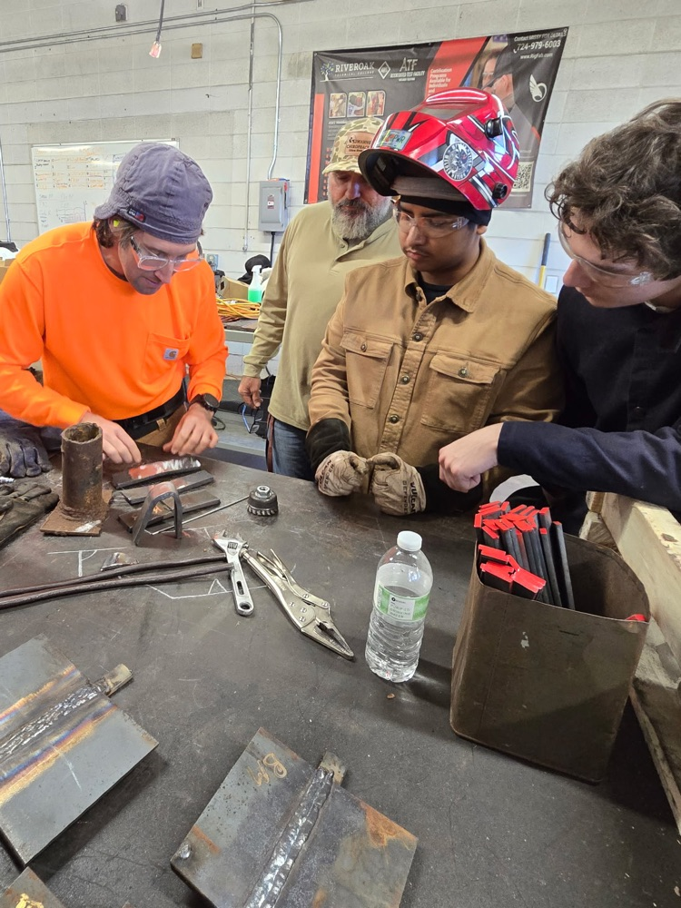 welders looking on at their work with instructor Mercer