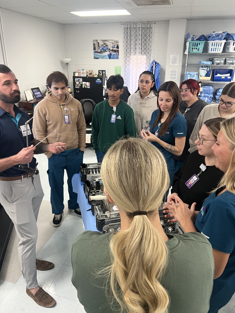 Surgical Technology students gathered around Jacob Brown learning about instruments