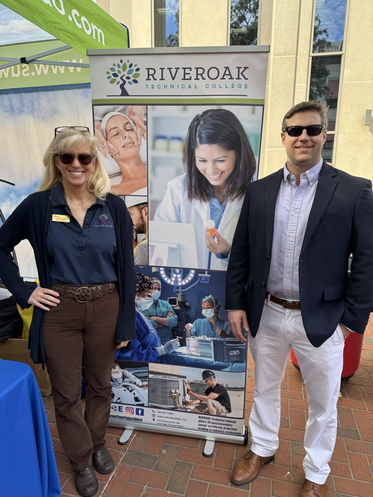 Julie Ulmer and Clay Tomlinson in front of RIVEROAK sign