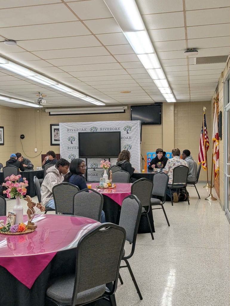 Multiple students sitting at tables eating breakfast